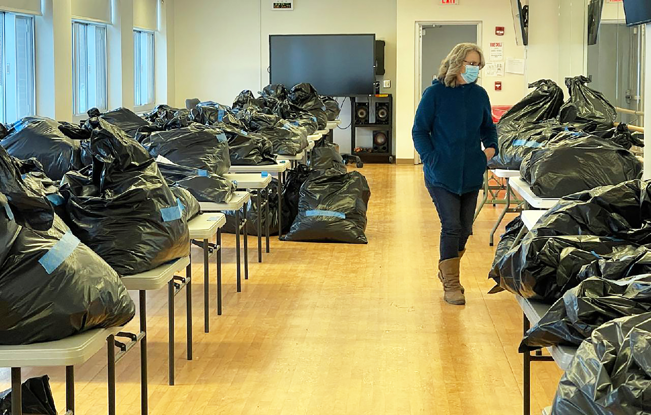 A volunteer walks past tables of clothing donations