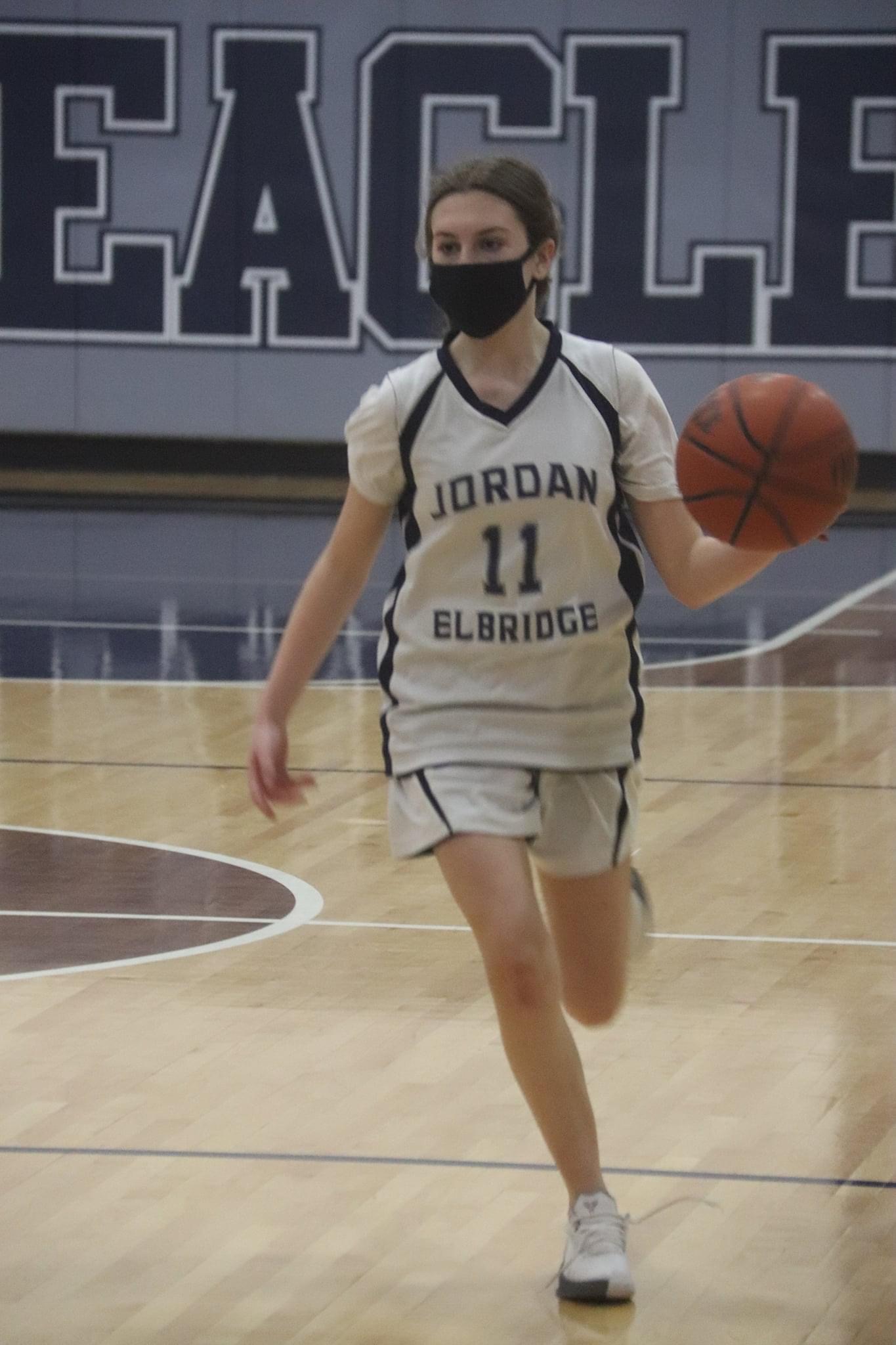 JE student dribbles a basketball during a home game