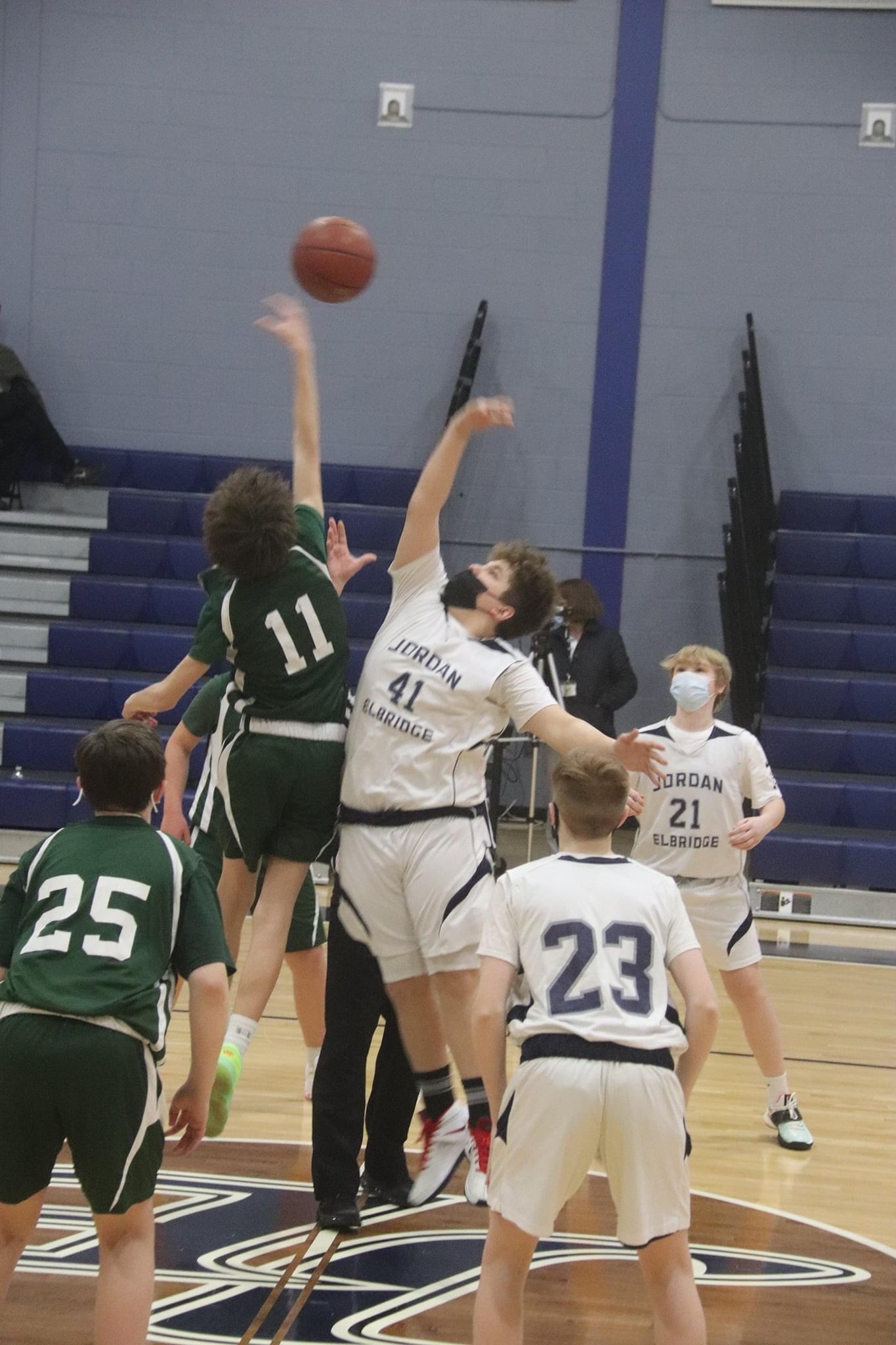 JE students jump to gain control of the ball during a basketball game