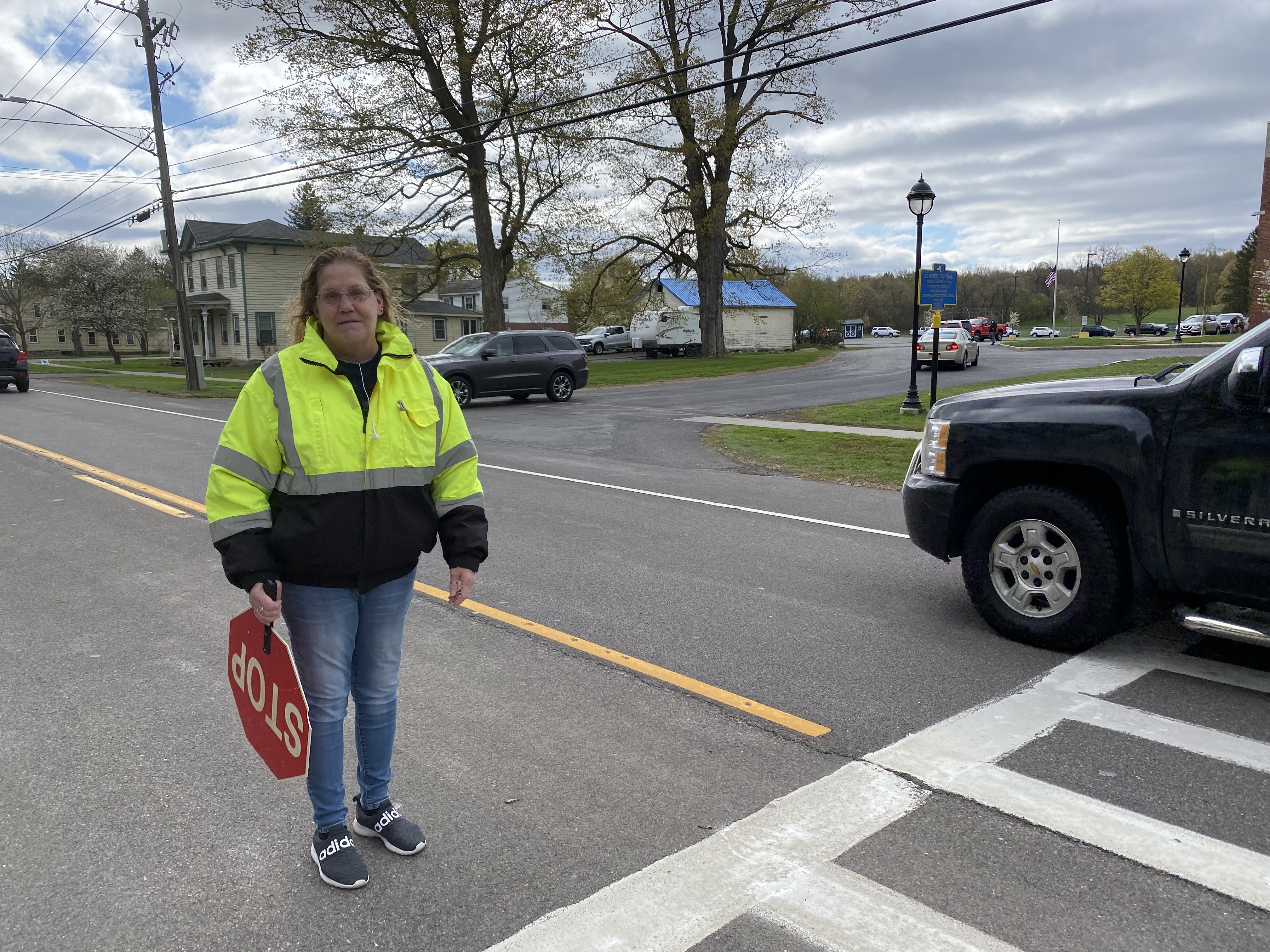 Crossing Guard Jeanine Nolte directs vehicle in front of Elbridge Elementary