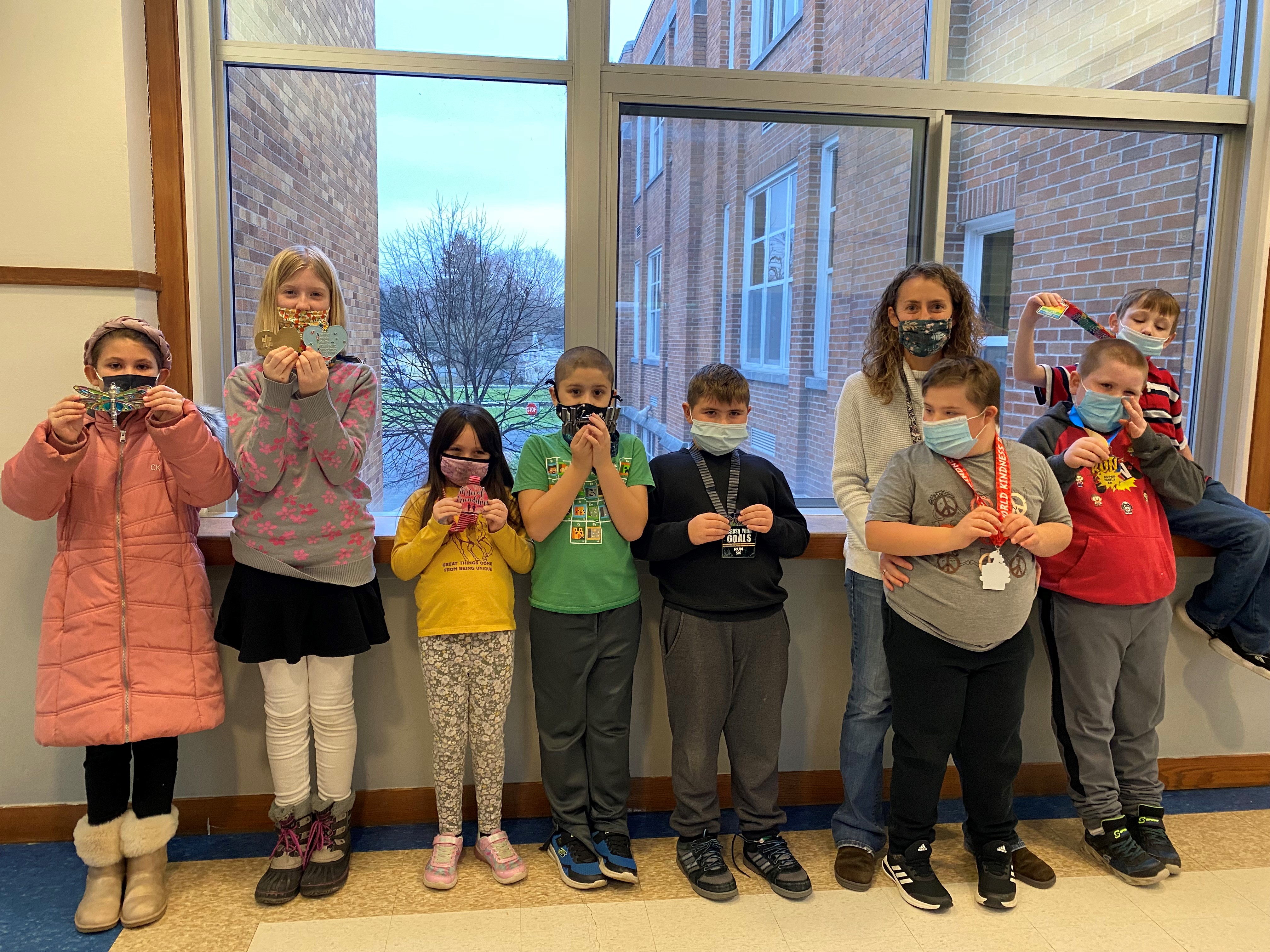 Beth Brunelle gives Mary Maestri's students her running trophies, collected across 11 races in 2021