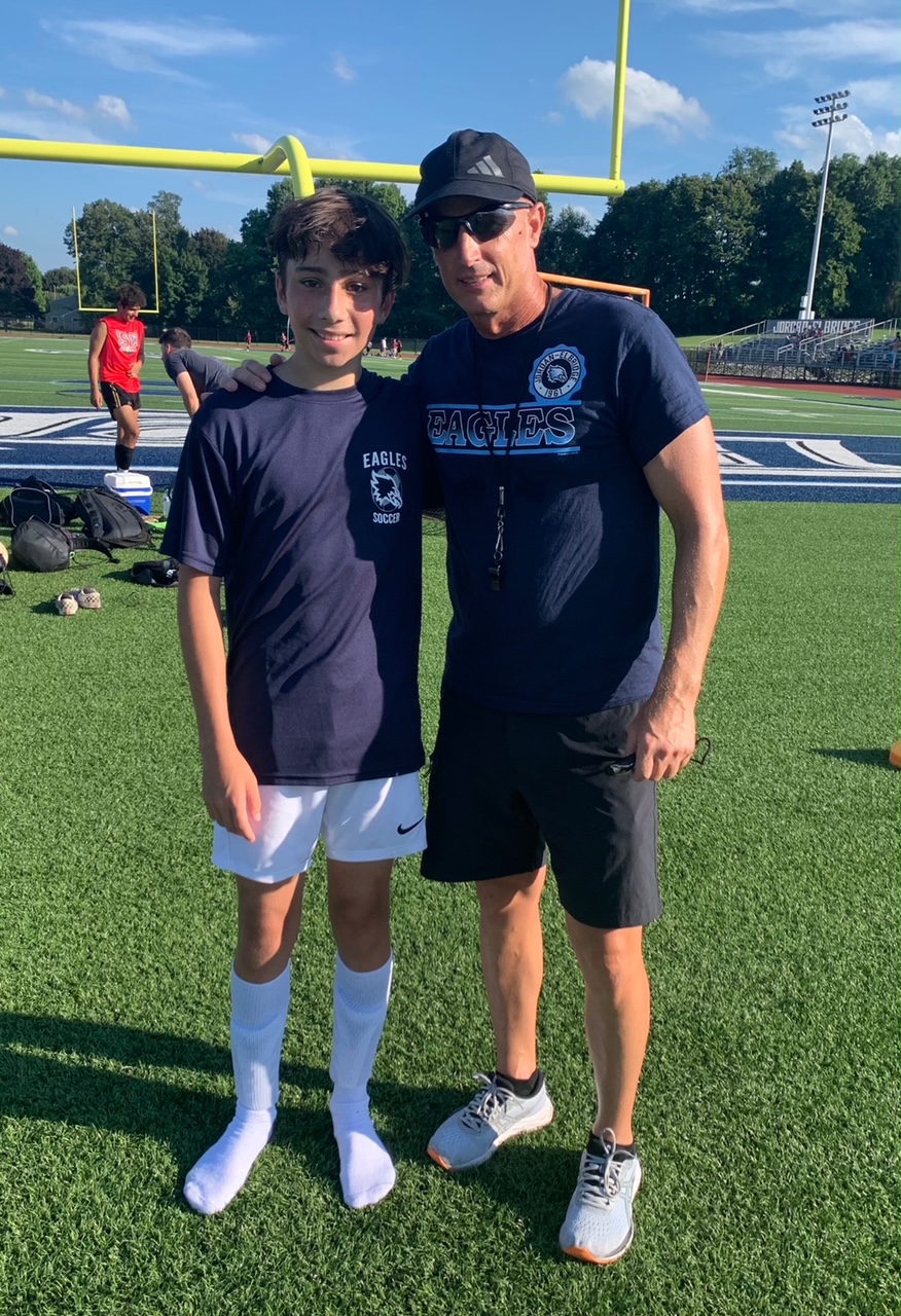 A student poses with Coach Martin during summer soccer league