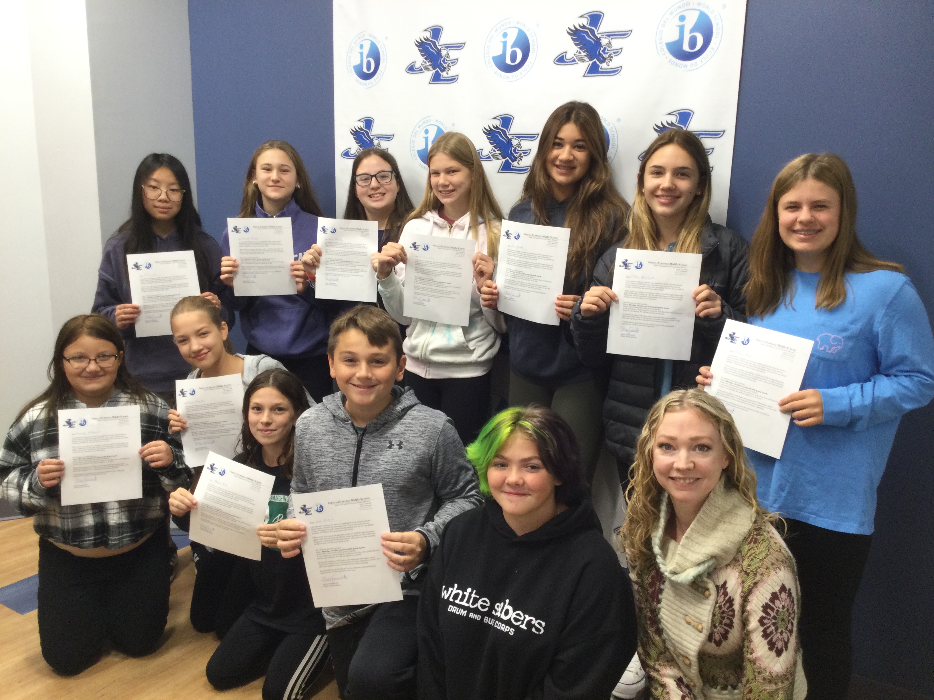 A group of JEMS students hold up certificates after being accepted into the National Junior Honor Society